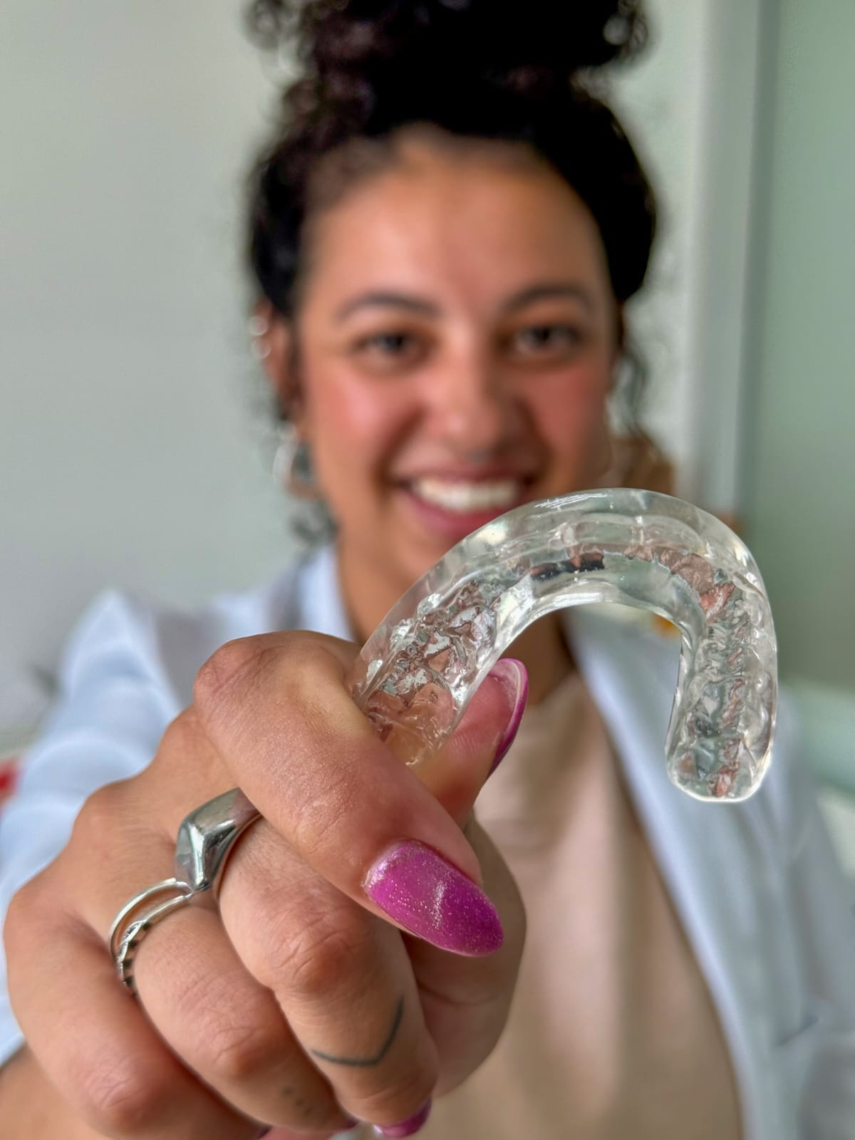 Dra. Maria Gabriela segurando uma placa oclusal transparente confeccionada sob medida